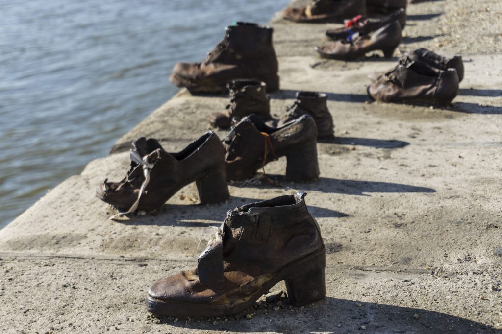 Photo of different brass boots and shoes at the edge of the Danube River in a touching tribute to lives lost during WW2 and the Holocaust