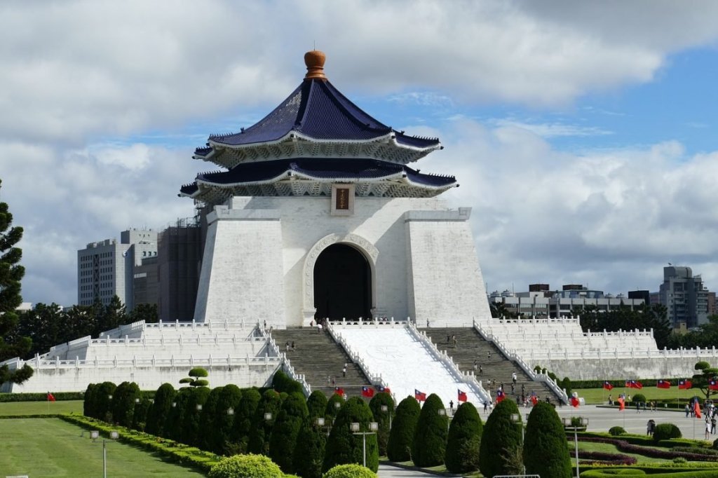 a view of a giant pagoda-style building in taipei with skyline behind it and red flags of taiwan