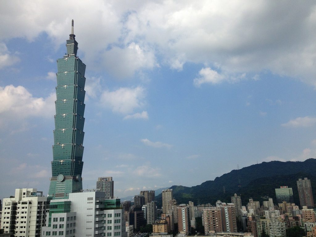 view of the taipei 101 towering in the sky looking beautiful over the skyline, like tiered boxes of blue glass architecture