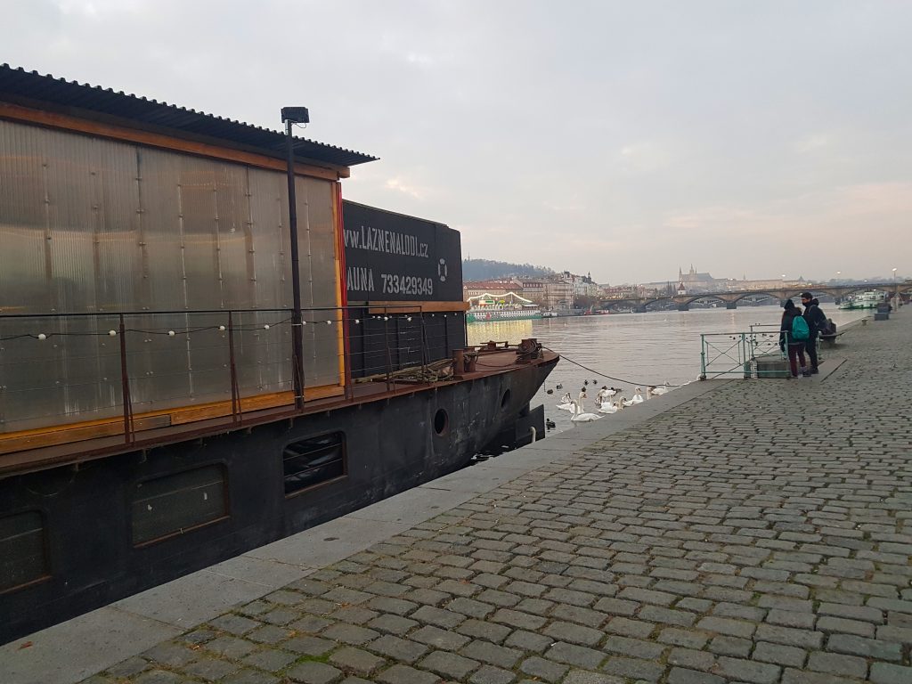 A floating barge on the Vltava River in winter called the Lazne na Lodi, where you can enjoy a sauna and then jump into the Vltava River afterwards, on the Naplavka River Bank.