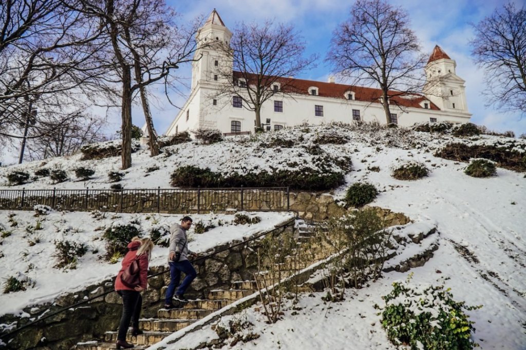 View of the stairs leading up to Bratislava Castle in the winter with two tourists walking up the stairs.