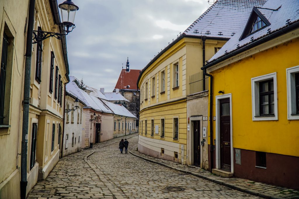 Two people walking down a cobblestone street in Bratislava Slovakia on a winter day