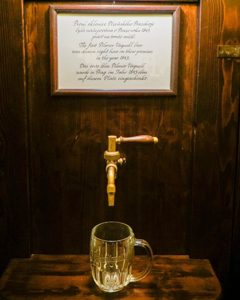 A sign in cursive handwriting at a bar in Prague telling the visitors that this is the original tap where the first Pilsner Urquell was ever poured.