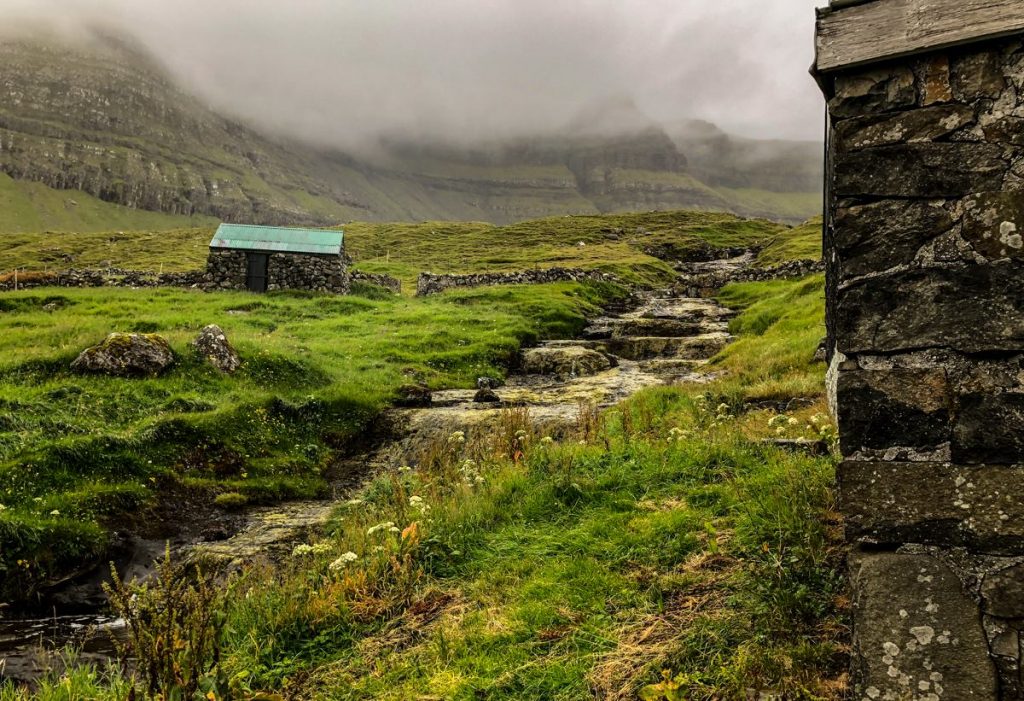 abandoned stone buildings and fog covered hills