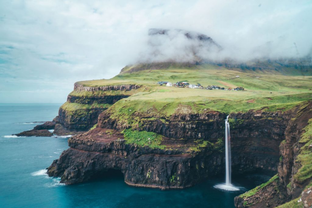 a waterfall emptying out into the sea below in the cute village of gasaladur