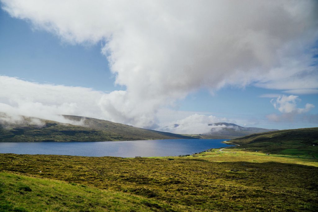 a calm lake with incoming fog in the faroe islands