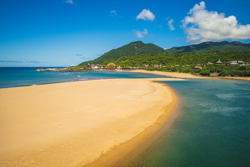 fulong beach in the taipei area with soft yellow sand and turquoise waters and green hills