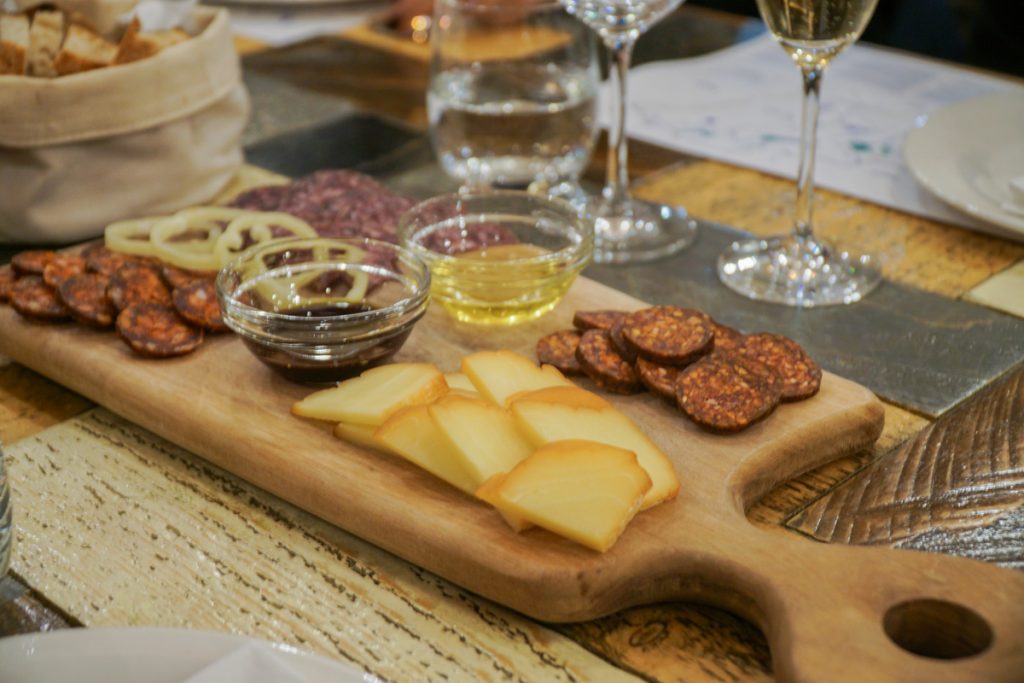 
White wine in a Budapest bar with a selection of cured meat cut into slices, served with pumpkin seed oil and olive oil and bread, as well as slices of cheese.
