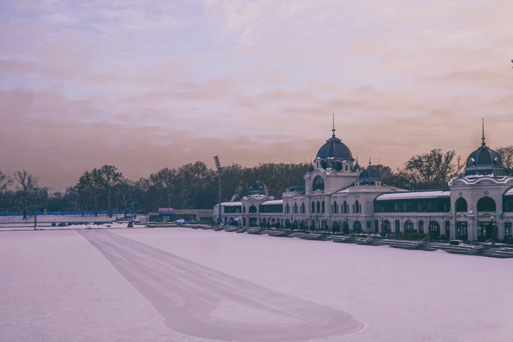 Sunset colors in Budapest in winter overlooking an ice rink near one of the major city parks. Sky is pink and blue pastel colors. 