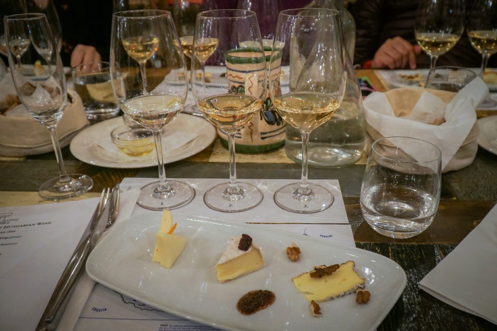 Three glasses of white wine for tasting, with several pieces of cheese, while attending a wine tasting class in Budapest in winter.