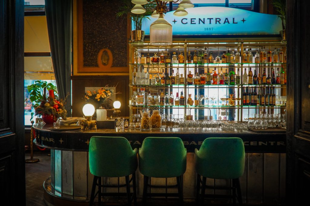 Three green velvet stools at the Budapest cafe called Central Cafe  which dates back to 1887 as stated on the blue sign at the bar.