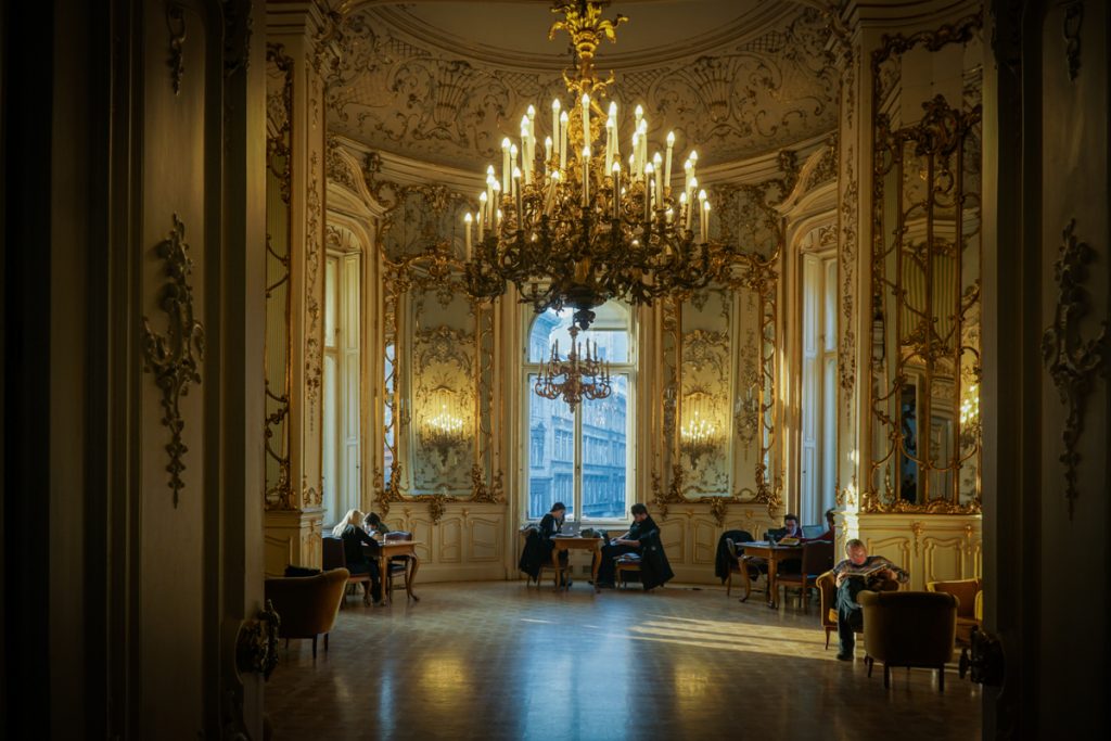 A chandelier in the reading room of the most scenic part of the Budapest library with people sitting and enjoying some books