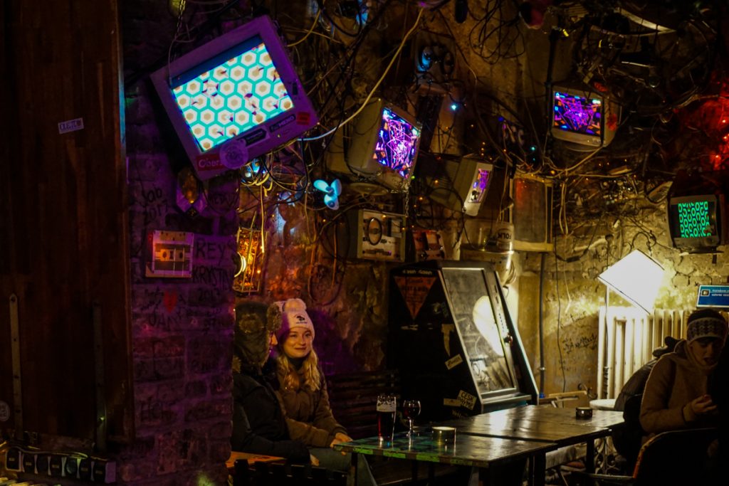 Person in a ruin bar with a hat on, sitting a table with lots of funky design and interior detail of a ruin bar