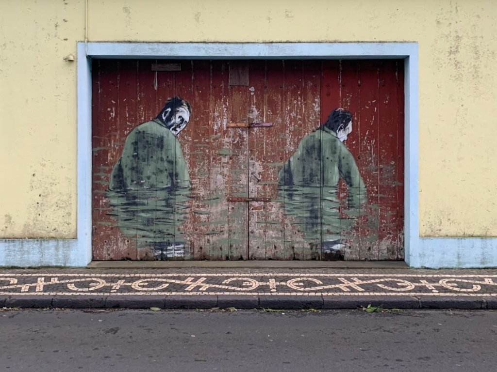 street art of two men's portraits on a garage door. yellow and red.