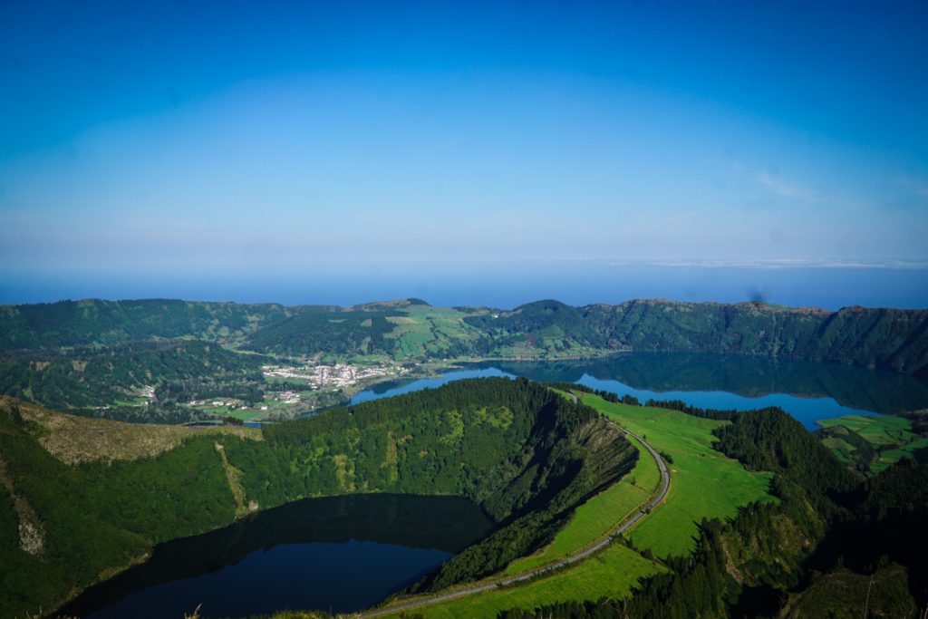 a volcanic crater filled with lake water and a lake down below at a popular miradouro viewpoint in sao miguel 