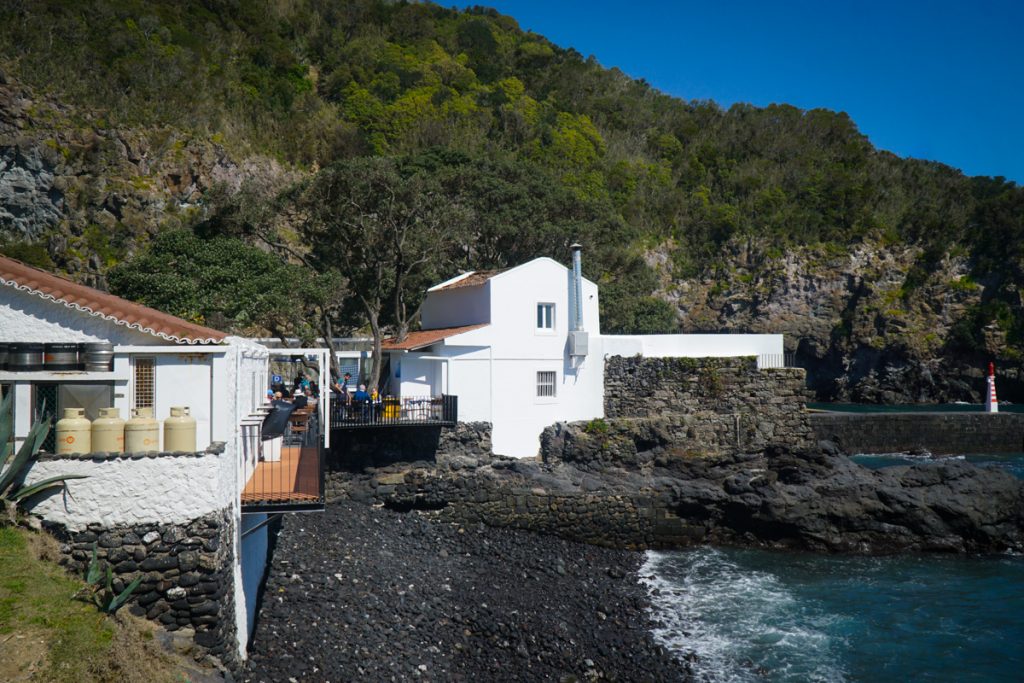 black sand beach next to a restaurant on the ocean