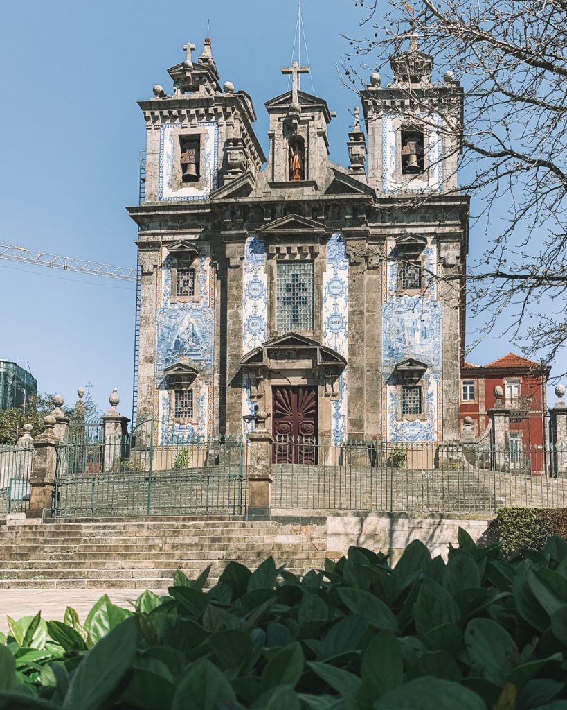 the azulejo-covered church of ildefonso in porto with white and blue tiles and stairs leading up to the church