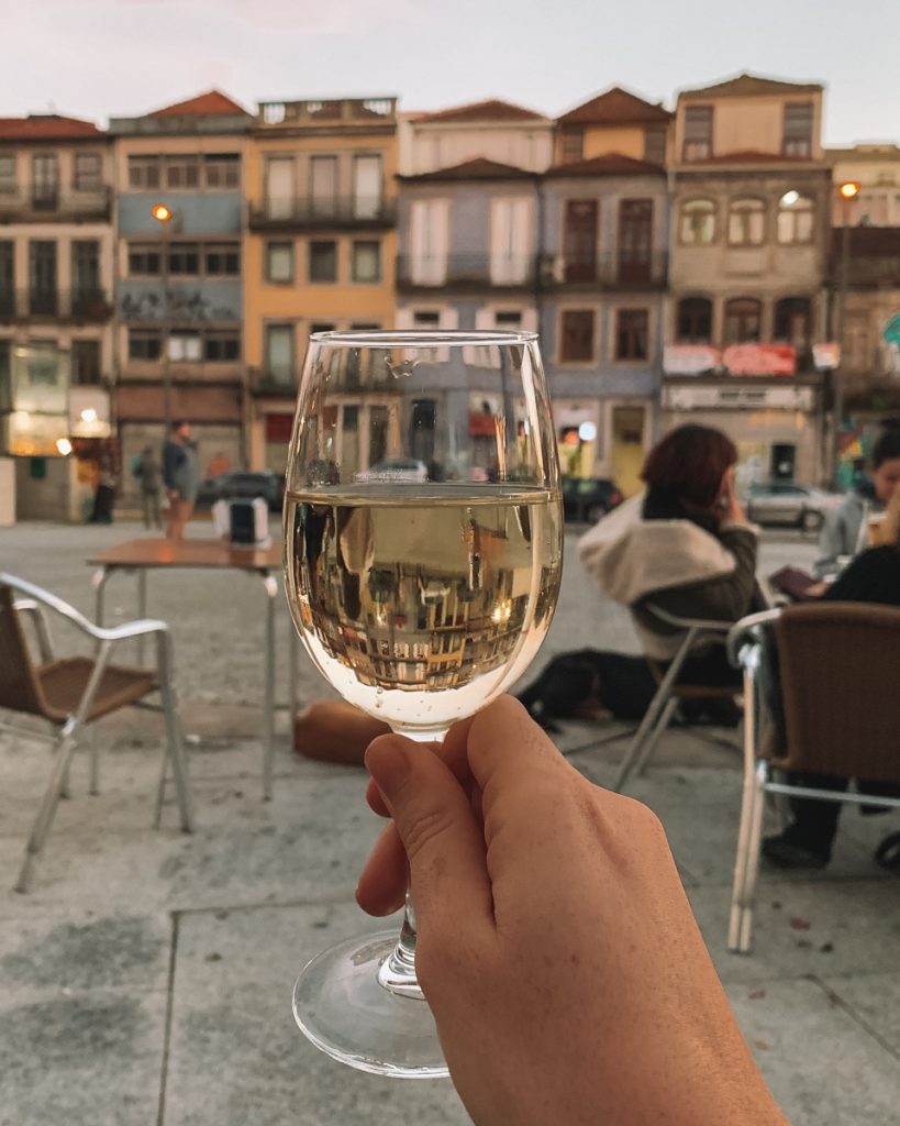 glass of white wine out in the street in porto while enjoying a sunset