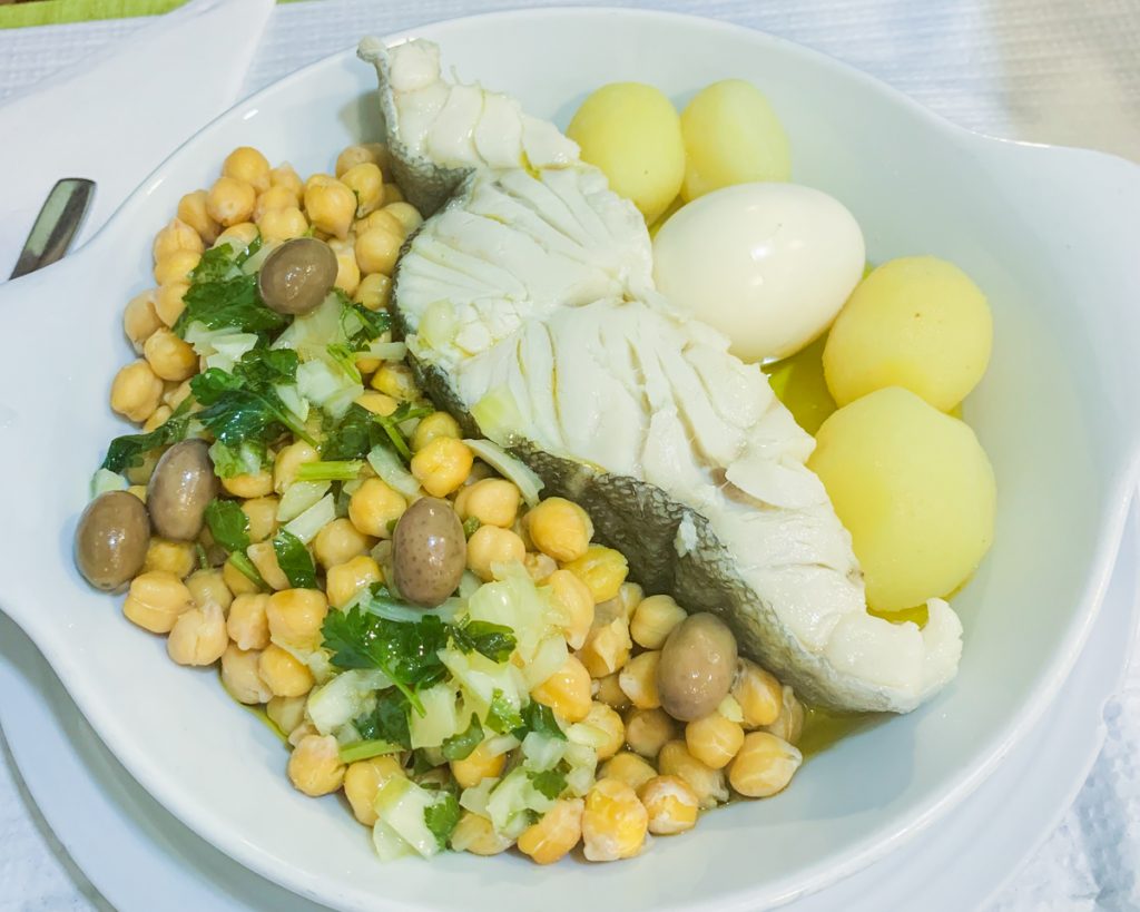 a piece of codfish with beans and potatoes and an egg