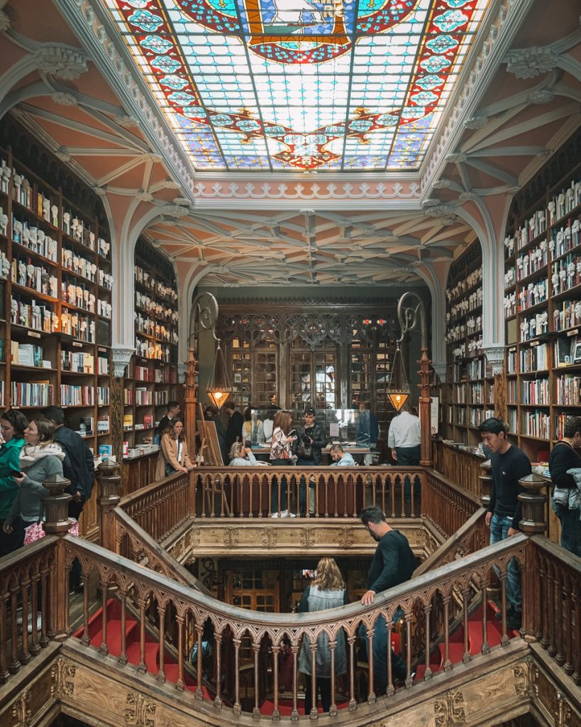 interior of a busy but beautiful bookstore livraria lello with stained glass and an ornate staircase
