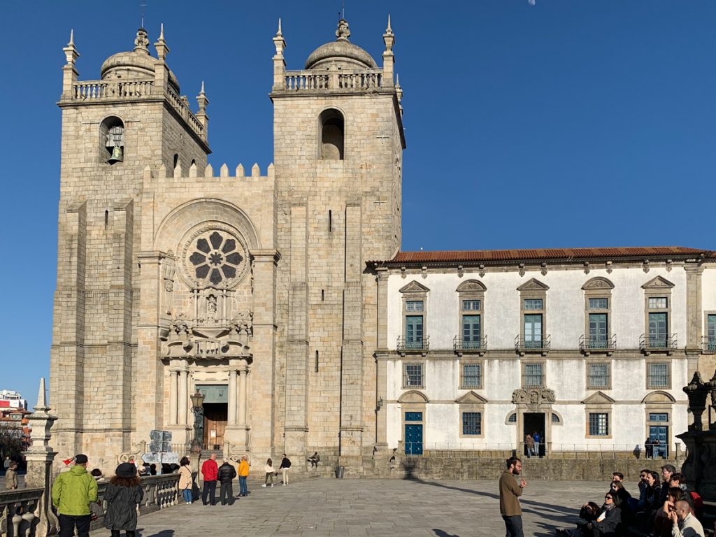 the facade of the porto cathedral (se do porto) on a sunny day with two towers and a circular stained glass window