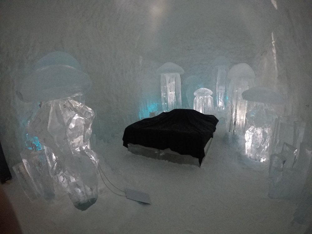 The interior of the Ice Hotel in Sweden with ice sculptures and a bed covered in a reindeer skin 