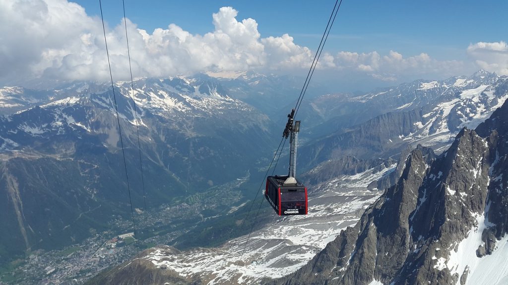 red cable car going up a steep snowy mountain to chamonix mt blanc