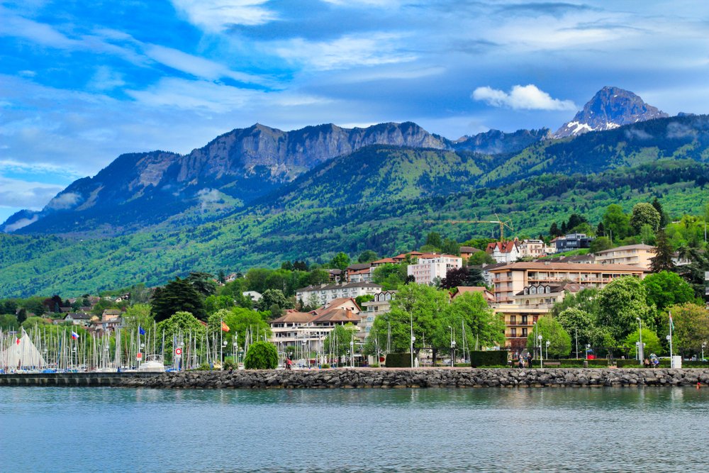 the beautiful french village of evian, home of the mineral water, on a sunny day with light clouds, on the waters of lac leman