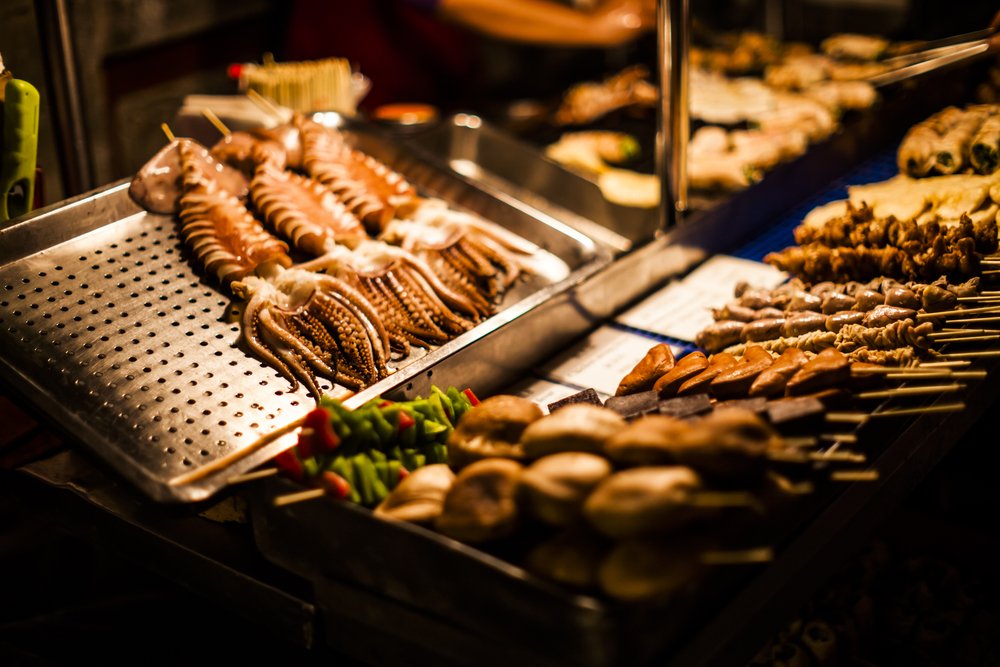 food served at a night market in dim light, squid and other skewers