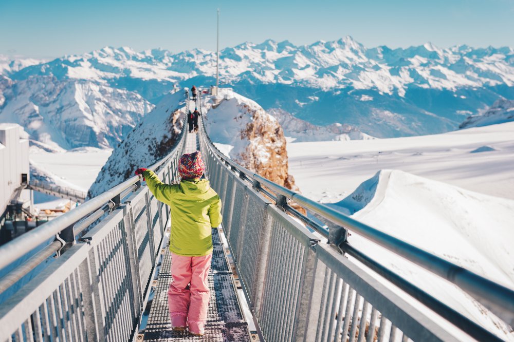 a small child in a green jacket and pink pants on a glacier walk in the swiss glaciers and mountains