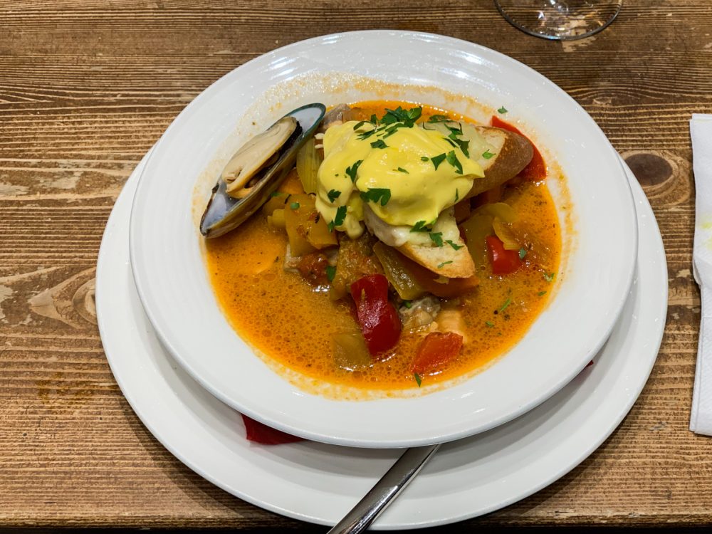 a bouillabaisse inspired soup with a hollandaise like sauce on top of a slice of baguette