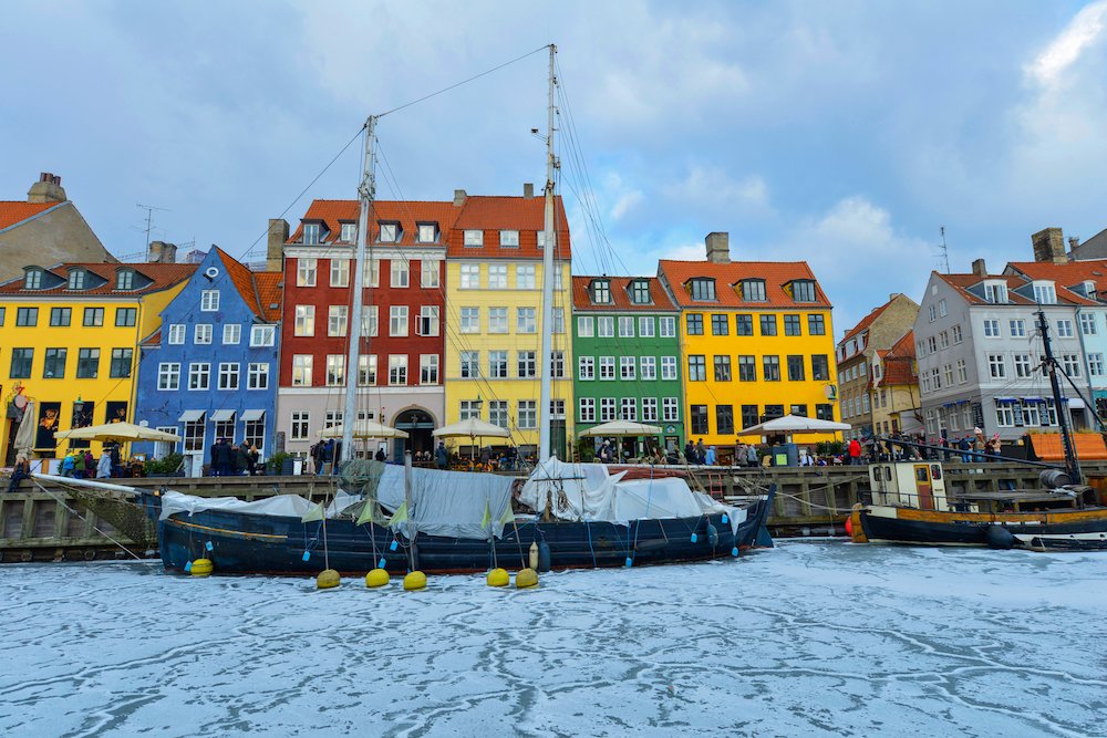 Brilliantly painted houses in yellow, green, red, and blue, in front of a frosty canal with a boat