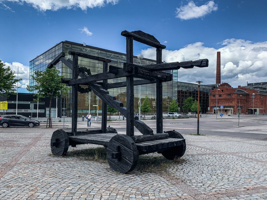 a strange wooden piece of art  near the downtown skyline of lahti