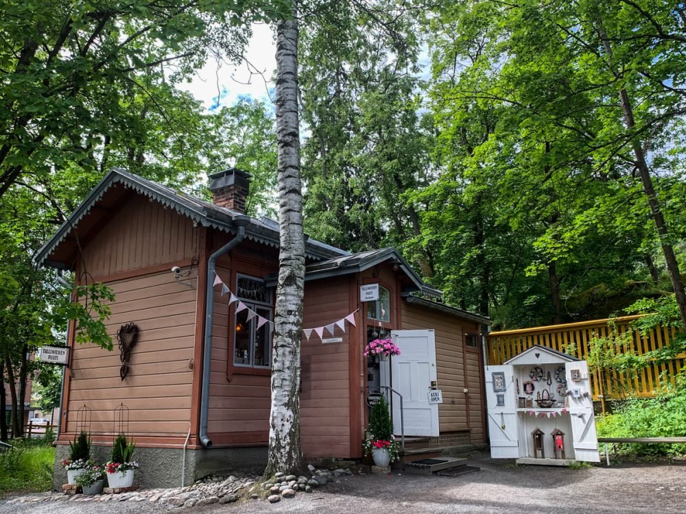 cute wooden building with a shed-like building in a forest with flags and flowers