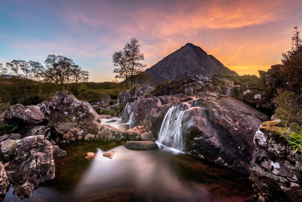 Mountain with waterfall in foreground at sunset