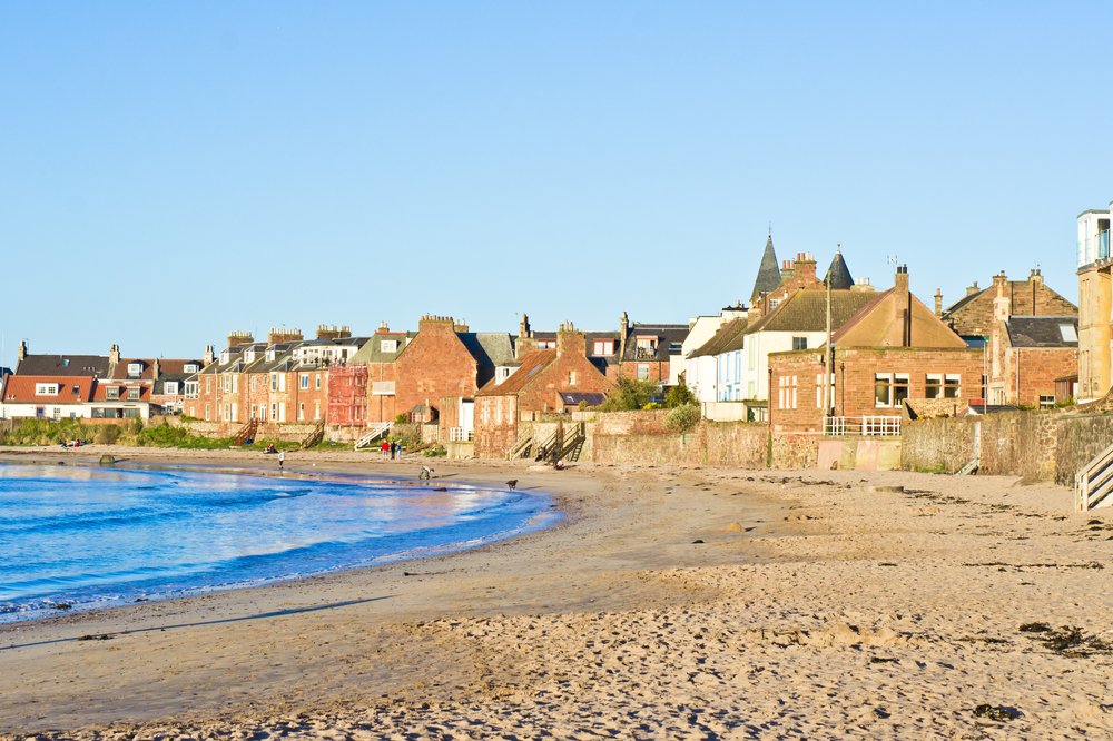 Sandy beach on sunny day with houses on shore