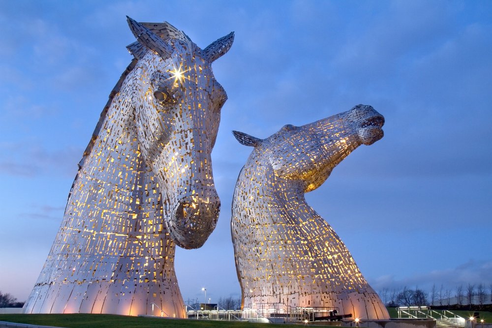 Two giant horse head sculptures lit up at night