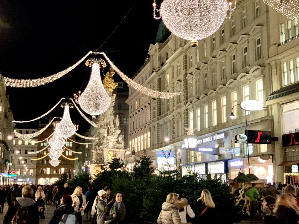 A crowded street with lots of tourists walking under the lights in the festive lanterns.