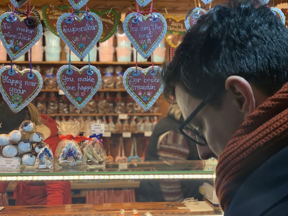 Allison's partner with a studious look on his face trying to pick out the right cookie at a market