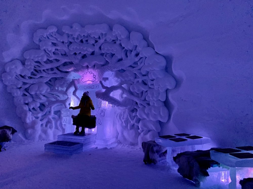 The ice bar and restaurant in the Tromso Ice Domes with reindeer pelts on seats carved out of ice and tables with placemats on them