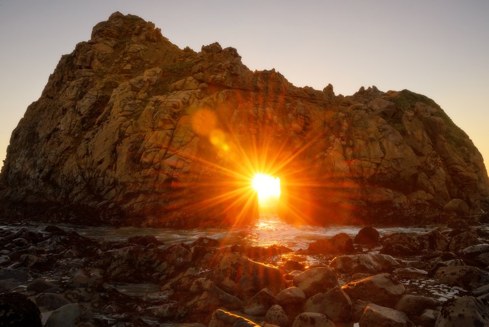 sun burst going through the keyhole arch at pfeiffer beach