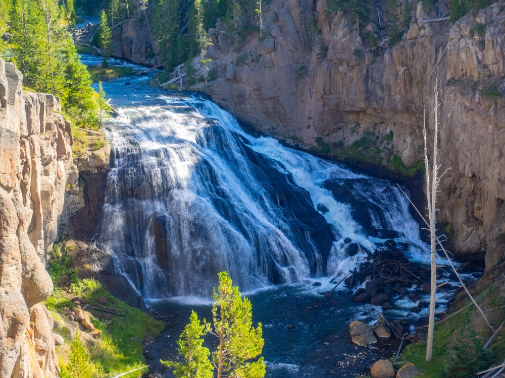 A waterfall in a river going over the steps of a tiered rock formation, forming a veil shape.