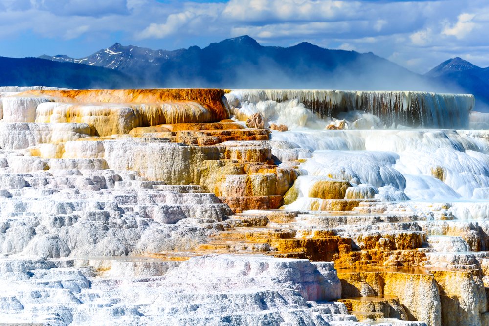 White and rust-colored calcium deposits form a travertine staircase of a hot spring at Mammoth Hot Springs, a must on your 2 days in Yellowstone.
