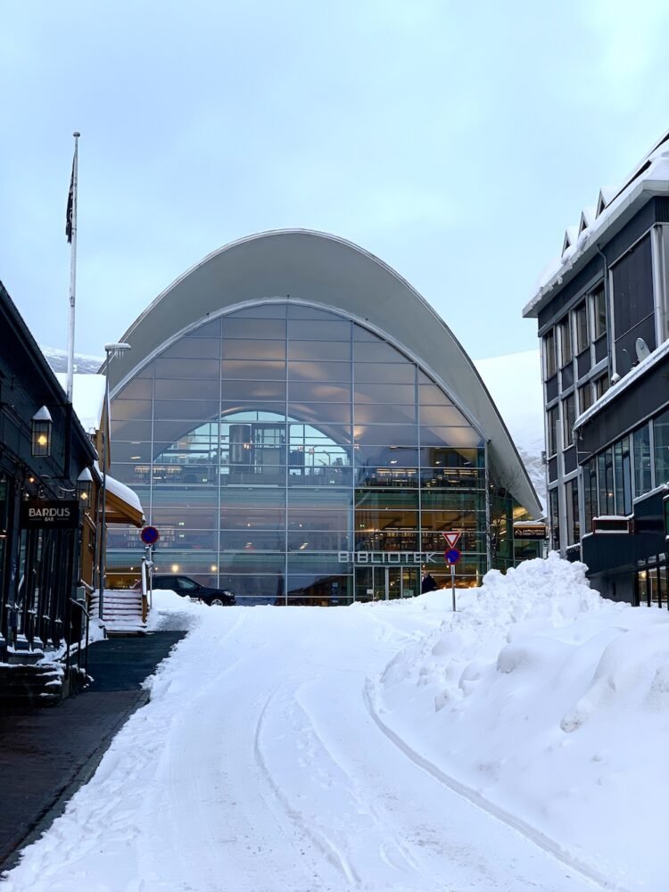 Intriguing modern glass architecture of the Bibliotek, the tromso library, on a street filled with snowfall