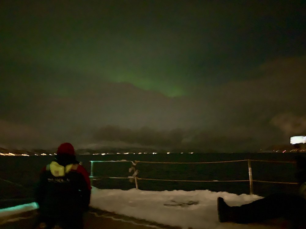 Allison looking up a tiny glimmer of the Northern lights seen over the city of Tromso while on the fjord sailing