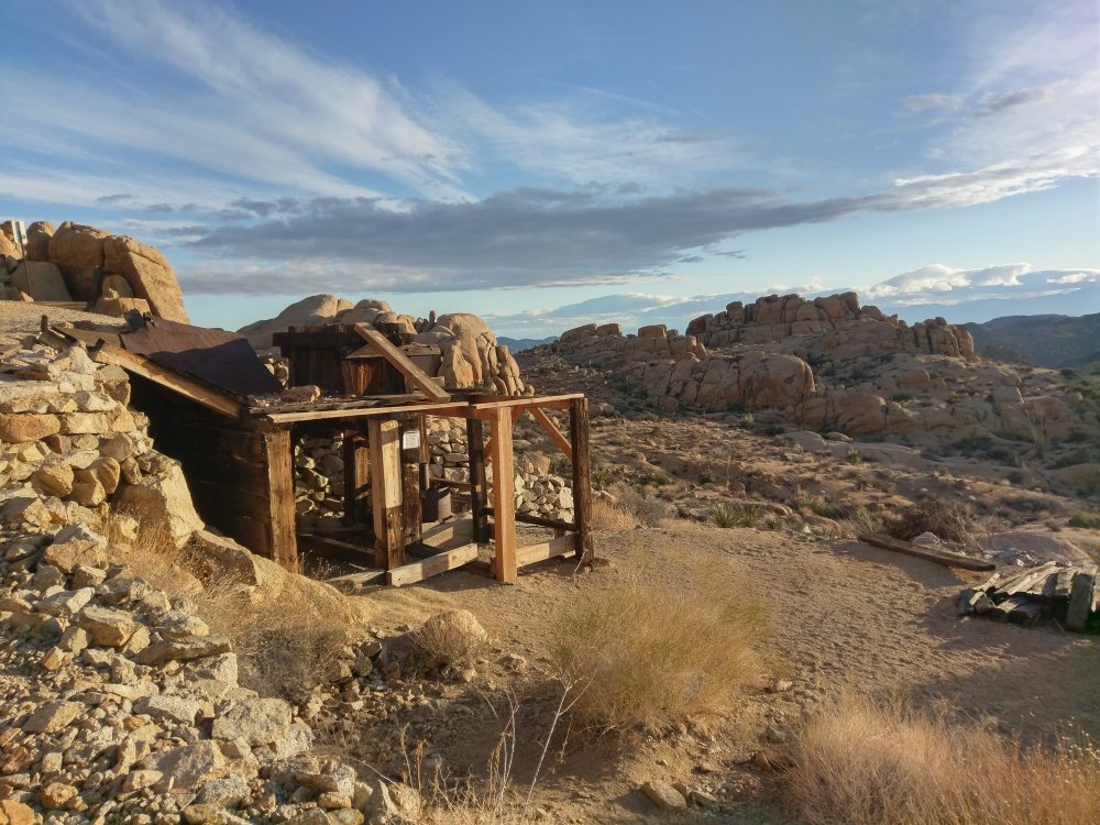 A view of an abandoned gold mine held up by planks in the rocky desert atmosphere of Joshua Tree National Park