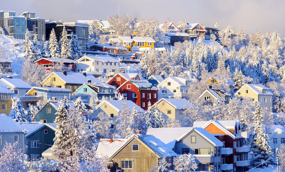 colorful houses in red, yellow, blue, etc. of the city of tromso covered in snow in the winter months where the city is a delightful wonderland.