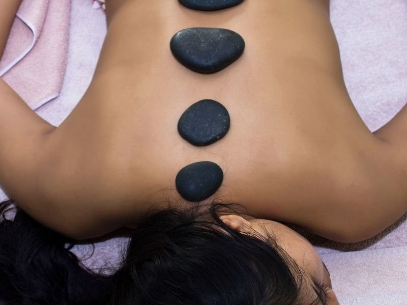Stones on a woman's back as she lays face down on a massage table