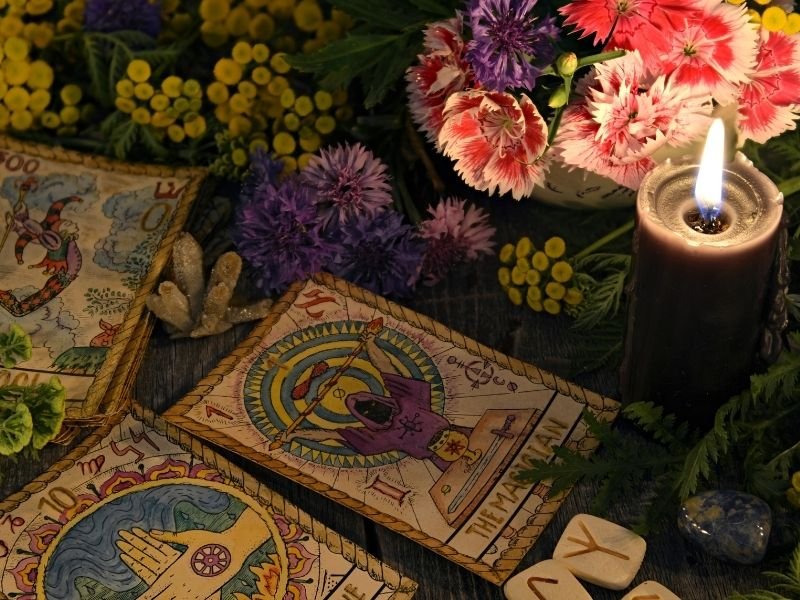Tarot cards with a lit candle and flowers