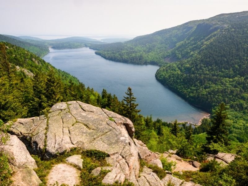 looking down on a lake in acadia national park from a rock at the top of a hiking area